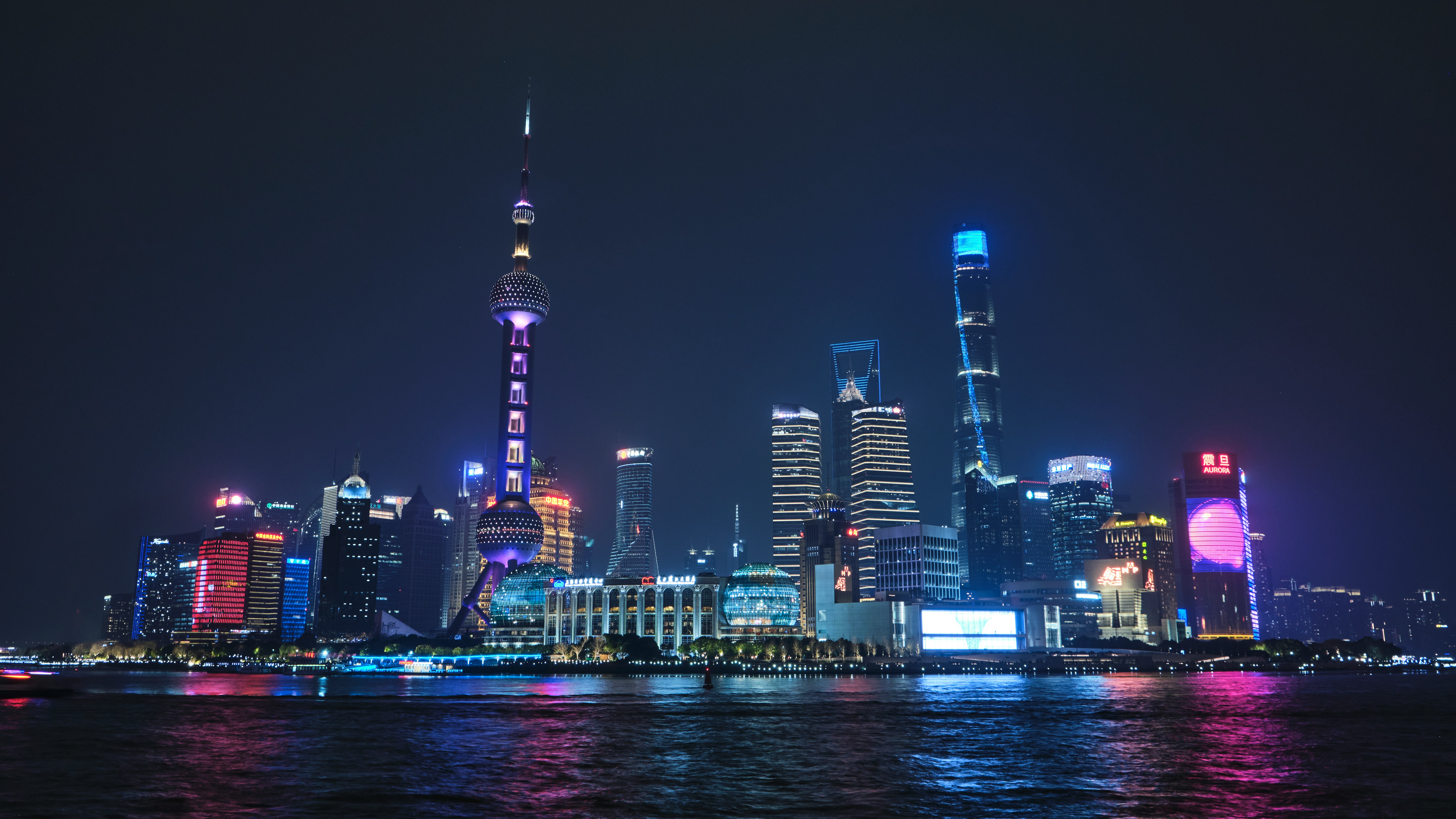 Lujiazui at night seen from the Bund — Oriental Pearl Tower lit purple, IFC and Shanghai Tower glowing blue across the Huangpu River