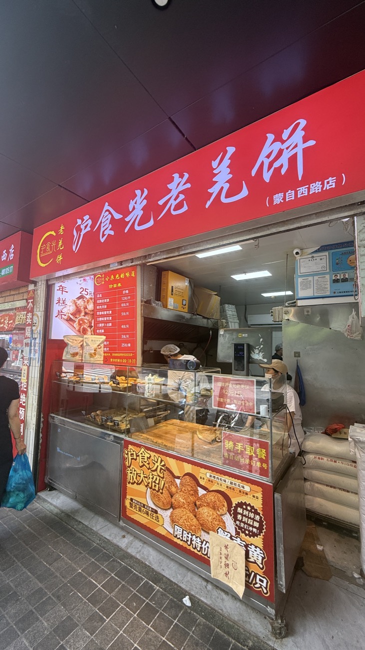 A bright-red Shanghai snack storefront next to Mengxi Market selling laohujiaozhua tiger-paw pastries and niangao rice cakes — a neighborhood food legend