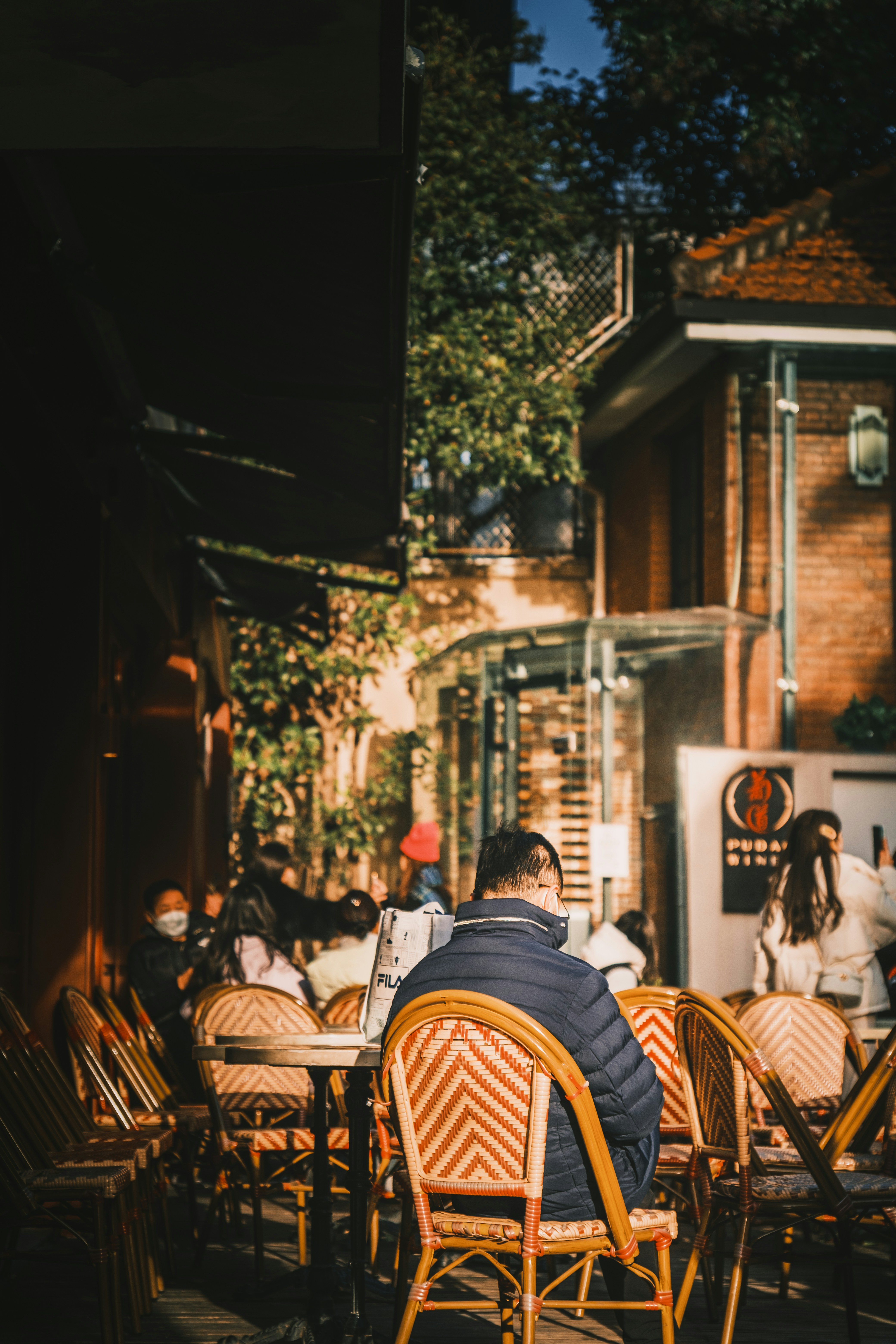 Ferguson Lane (武康庭) outdoor café terrace — red-and-cream chevron rattan chairs, brick courtyard, golden late-afternoon light